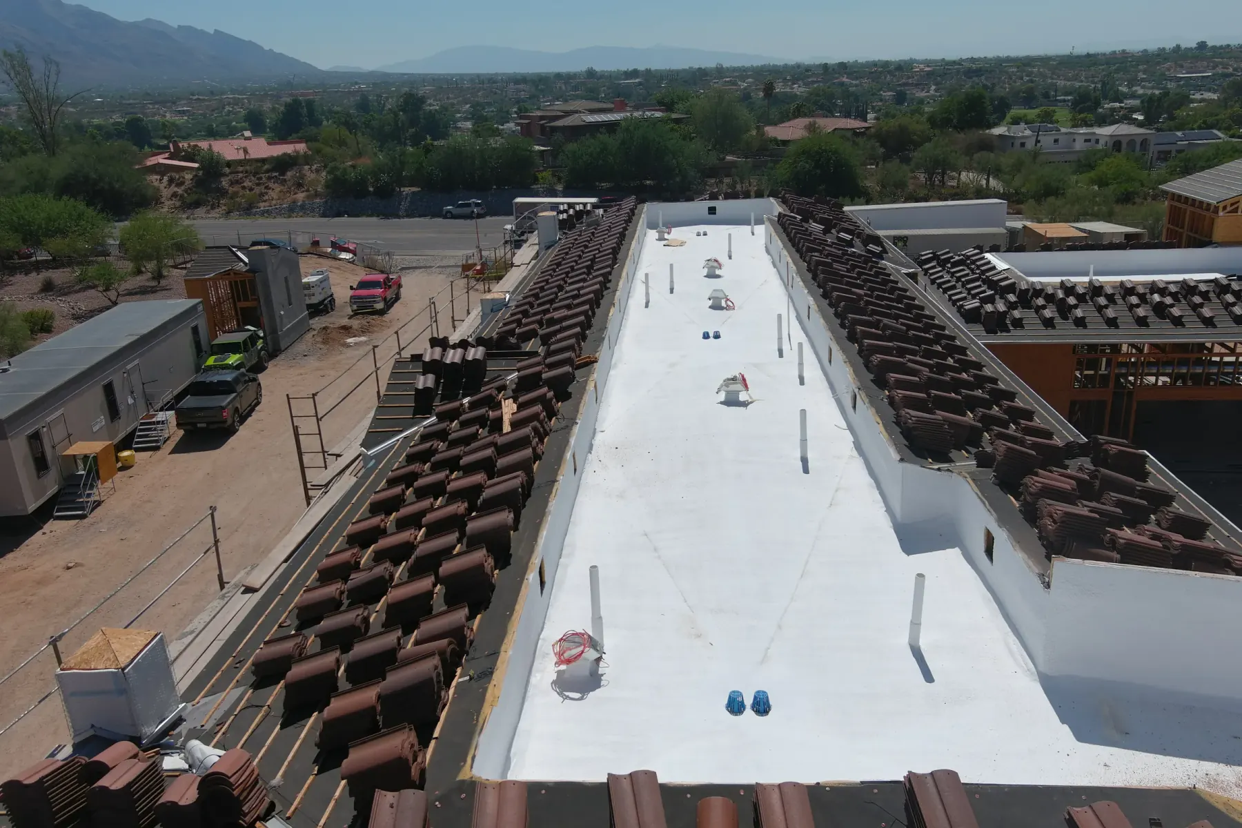 Completed low-slope roof beside pitched tile roof sections